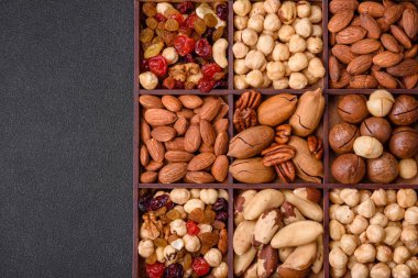 Kavrulmuş macadamia fındığı, ceviz, ceviz, ceviz, badem, kuru üzüm karışımı koyu beton bir arka planda.