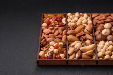 Kavrulmuş macadamia fındığı, ceviz, ceviz, ceviz, badem, kuru üzüm karışımı koyu beton bir arka planda.