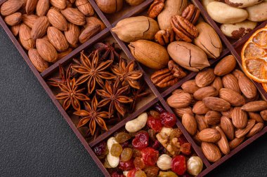 Kavrulmuş macadamia fındığı, ceviz, ceviz, ceviz, badem, kuru üzüm karışımı koyu beton bir arka planda.