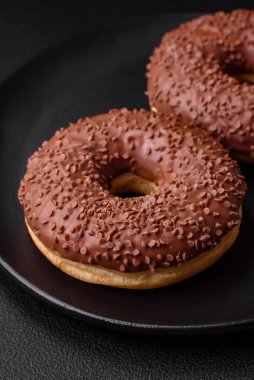 Koyu beton bir zemine çikolata parçacıkları serpiştirilmiş lezzetli çikolata kaplı donut.