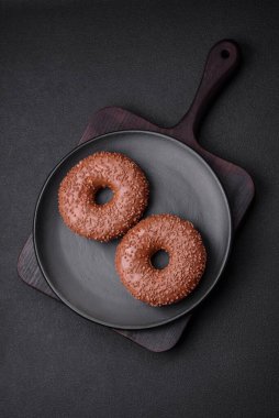 Koyu beton bir zemine çikolata parçacıkları serpiştirilmiş lezzetli çikolata kaplı donut.