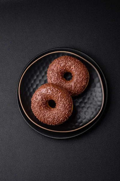stock image Delicious chocolate glazed donut sprinkled with chocolate chips on a dark concrete background