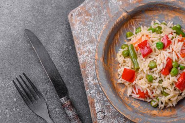 Lezzetli haşlanmış pirinç, biber, bezelye, kuşkonmaz fasulyesi ve havuç ve beton kaplama.