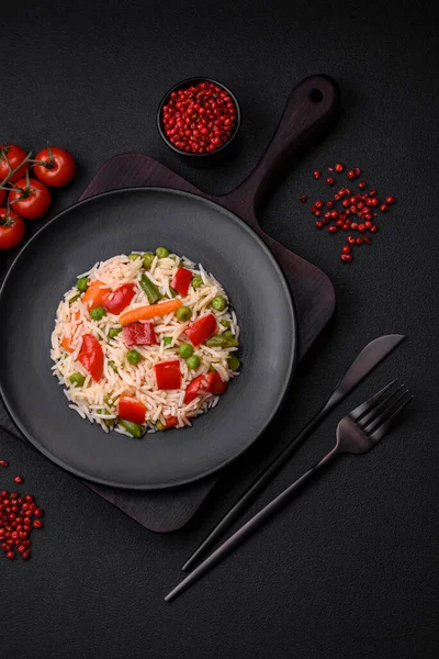 stock image Delicious boiled rice with peppers, peas, asparagus beans and carrots on a textured concrete background