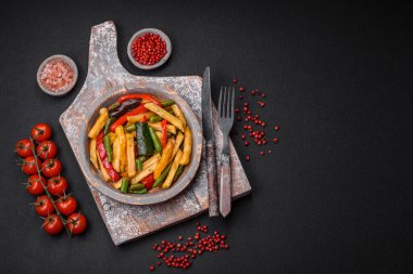 Lezzetli kızarmış patates, dolmalık biber, kuşkonmaz fasulyesi, tuz ve baharatlar, koyu beton bir arka planda.