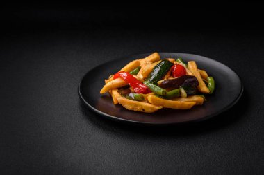 Lezzetli kızarmış patates, dolmalık biber, kuşkonmaz fasulyesi, tuz ve baharatlar, koyu beton bir arka planda.