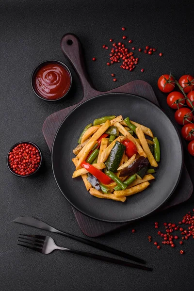 stock image Delicious fried potatoes with bell peppers, asparagus beans, salt and spices in a plate on a dark concrete background