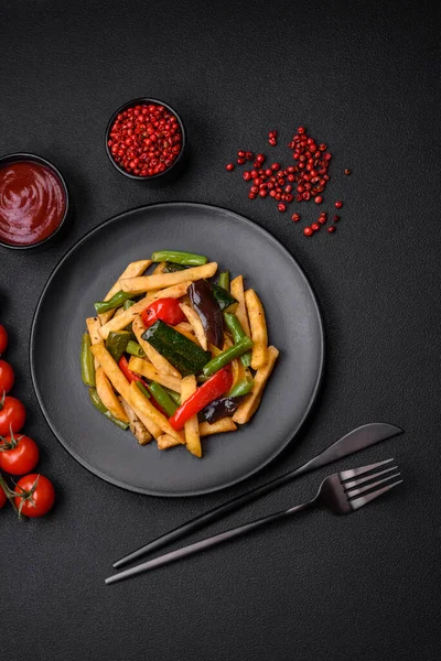 stock image Delicious fried potatoes with bell peppers, asparagus beans, salt and spices in a plate on a dark concrete background