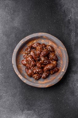 Soya sosunda kızartılmış tavuk kalbi. Tuzlu ve baharatlı bir tabakta beton bir arka planda.