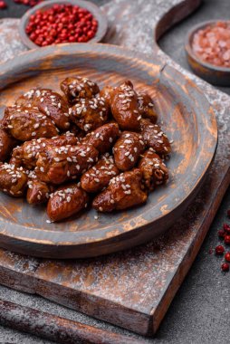 Soya sosunda kızartılmış tavuk kalbi. Tuzlu ve baharatlı bir tabakta beton bir arka planda.