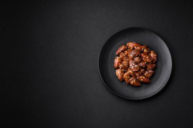 Soya sosunda kızartılmış tavuk kalbi. Tuzlu ve baharatlı bir tabakta beton bir arka planda.