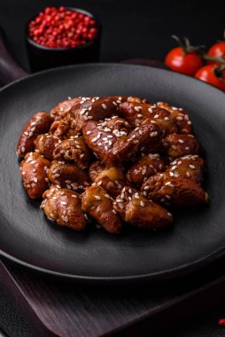 Soya sosunda kızartılmış tavuk kalbi. Tuzlu ve baharatlı bir tabakta beton bir arka planda.