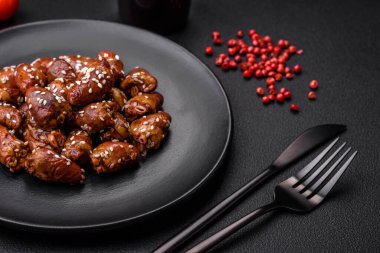 Soya sosunda kızartılmış tavuk kalbi. Tuzlu ve baharatlı bir tabakta beton bir arka planda.