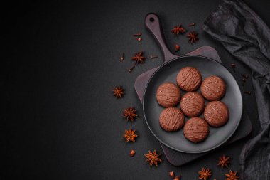 Siyah seramik tabakta, koyu beton bir zeminde lezzetli çikolatalı kurabiyeler.