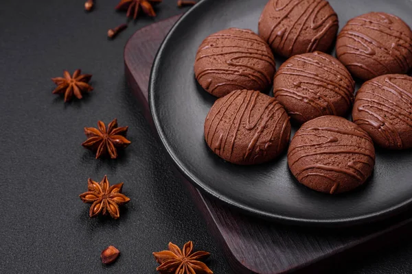 stock image Delicious sweet chocolate cookies on a black ceramic plate on a dark concrete background