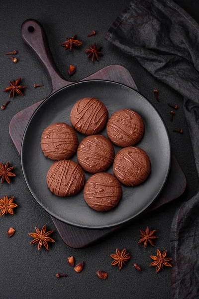 stock image Delicious sweet chocolate cookies on a black ceramic plate on a dark concrete background