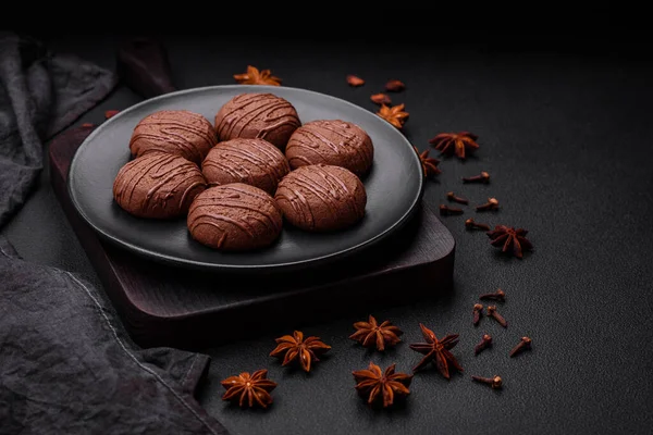 stock image Delicious sweet chocolate cookies on a black ceramic plate on a dark concrete background