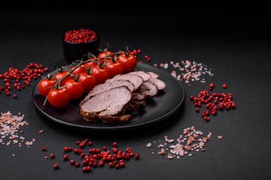 Tuzlu biftek, baharat ve otlar seramik tabakta koyu beton arka planda.