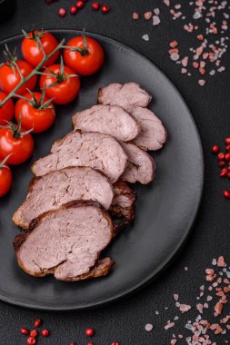 Tuzlu biftek, baharat ve otlar seramik tabakta koyu beton arka planda.