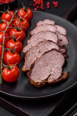 Tuzlu biftek, baharat ve otlar seramik tabakta koyu beton arka planda.