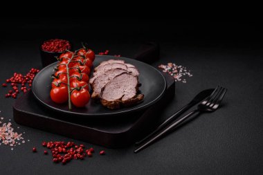 Tuzlu biftek, baharat ve otlar seramik tabakta koyu beton arka planda.