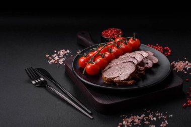 Tuzlu biftek, baharat ve otlar seramik tabakta koyu beton arka planda.