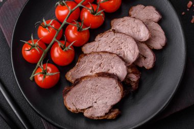 Tuzlu biftek, baharat ve otlar seramik tabakta koyu beton arka planda.