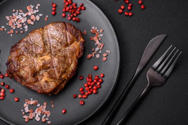 stock image Delicious juicy pork or beef steak grilled with salt, spices and herbs on a textured concrete background