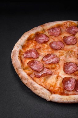 Salamlı, peynirli, domatesli, baharatlı ve esmer arkaplanlı taze pizza.