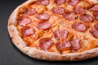 Salamlı, peynirli, domatesli, baharatlı ve esmer arkaplanlı taze pizza.