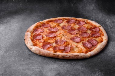 Salamlı, peynirli, domatesli, baharatlı ve esmer arkaplanlı taze pizza.