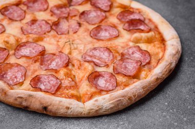 Salamlı, peynirli, domatesli, baharatlı ve esmer arkaplanlı taze pizza.