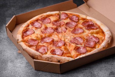 Salamlı, peynirli, domatesli, baharatlı ve esmer arkaplanlı taze pizza.