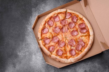 Salamlı, peynirli, domatesli, baharatlı ve esmer arkaplanlı taze pizza.