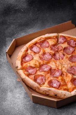 Salamlı, peynirli, domatesli, baharatlı ve esmer arkaplanlı taze pizza.