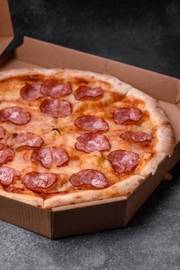 Salamlı, peynirli, domatesli, baharatlı ve esmer arkaplanlı taze pizza.