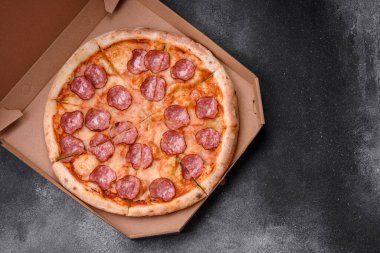 Salamlı, peynirli, domatesli, baharatlı ve esmer arkaplanlı taze pizza.