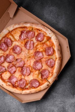 Salamlı, peynirli, domatesli, baharatlı ve esmer arkaplanlı taze pizza.