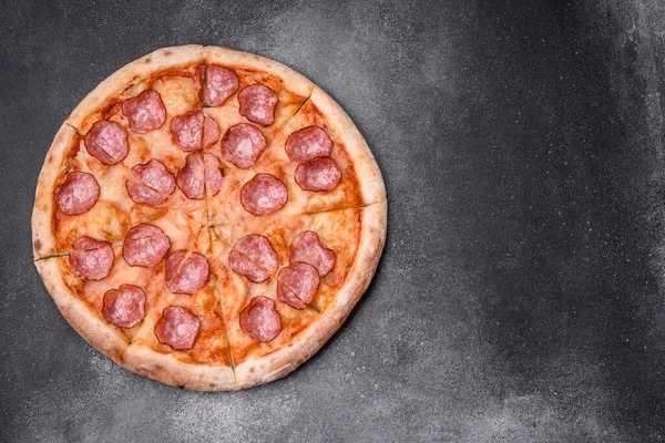 Stock image Tasty fresh pizza with salami, cheese, tomatoes, spices and salt on a dark concrete background