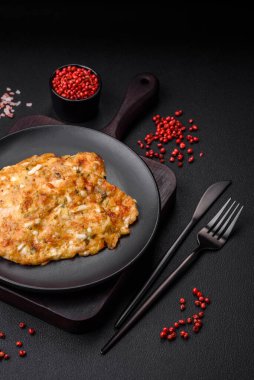 Lezzetli kızarmış tavuk göğsü hardal, tuz, baharat ve peynirli koyu beton arka planda.