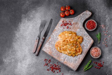 Lezzetli kızarmış tavuk göğsü hardal, tuz, baharat ve peynirli koyu beton arka planda.