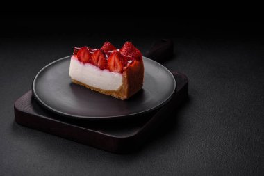 Çilekli, şuruplu ve desenli beton arkaplanlı peynirli leziz taze cheesecake.