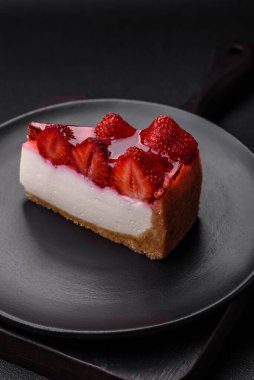 Çilekli, şuruplu ve desenli beton arkaplanlı peynirli leziz taze cheesecake.