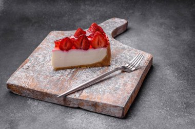 Çilekli, şuruplu ve desenli beton arkaplanlı peynirli leziz taze cheesecake.