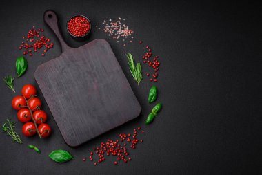 Koyu beton zeminde domates, tuz, baharat ve otlar pişirmek için gerekli malzemeler.