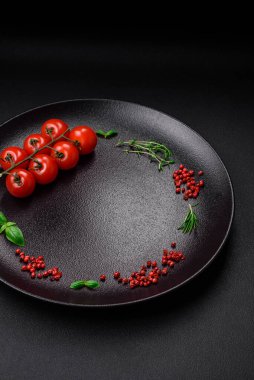 Koyu beton zeminde domates, tuz, baharat ve otlar pişirmek için gerekli malzemeler.