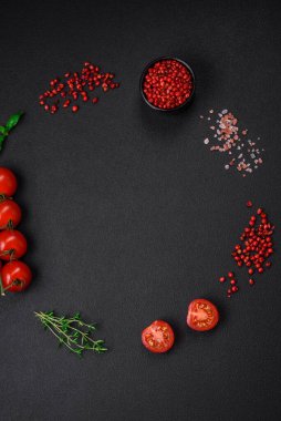 Koyu beton zeminde domates, tuz, baharat ve otlar pişirmek için gerekli malzemeler.