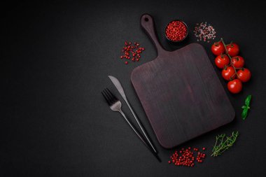 Koyu beton zeminde domates, tuz, baharat ve otlar pişirmek için gerekli malzemeler.