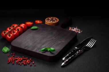 Koyu beton zeminde domates, tuz, baharat ve otlar pişirmek için gerekli malzemeler.