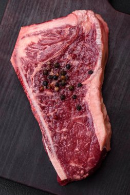 Taze taze taze taze New York bifteği, tuz, baharat ve çimento arka planda otlar.